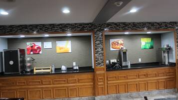 Zona de recepción de un hotel con mostrador, refrigerador y máquina de café.