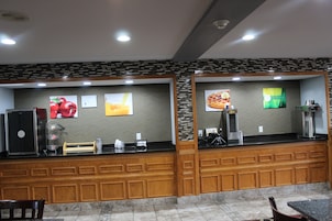 Zona de recepción de un hotel con mostrador, refrigerador y máquina de café.