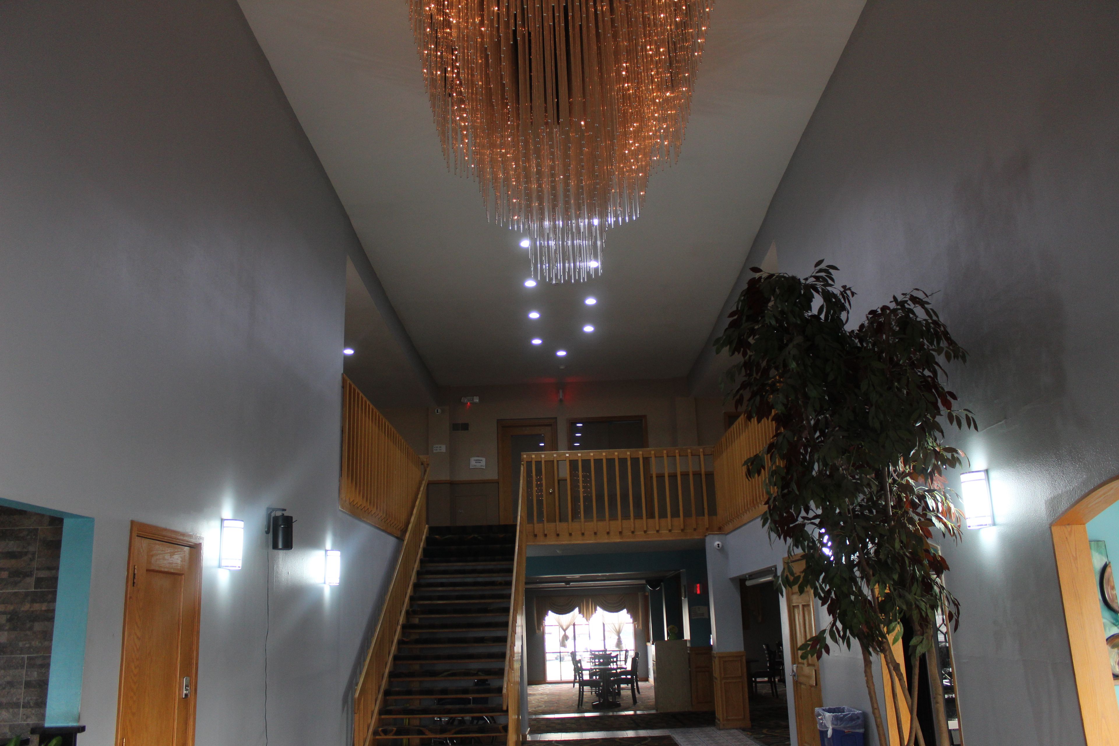 Un hall d’hôtel avec un escalier, un lustre et une plante en pot.