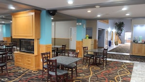 Un comedor de hotel con varias mesas y sillas, una chimenea y una alfombra estampada.