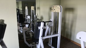 Un gimnasio con diferentes máquinas de ejercicio, incluyendo una máquina Smith y una prensa de pecho.