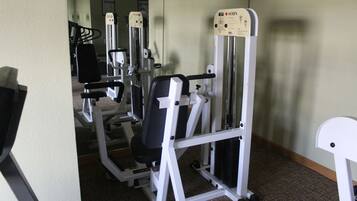 Un gimnasio con diferentes máquinas de ejercicio, incluyendo una máquina Smith y una prensa de pecho.
