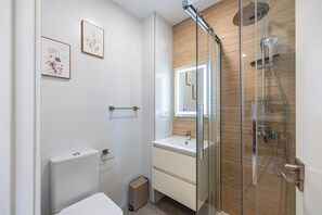 Een moderne badkamer met een douchecabine van glas, een toilet en een wastafel met spiegel.