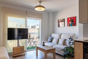Een moderne woonkamer met een flatscreen televisie, een bank, een salontafel en een eethoek met een tafel en stoelen.