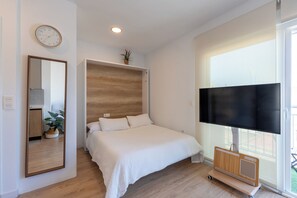Ein Schlafzimmer mit einem Bett, einem Fernseher, einem Spiegel und einer Pflanze.