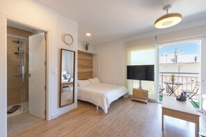 Een slaapkamer met een bed, nachtkastje, spiegel, plafondventilator en een raam met uitzicht.