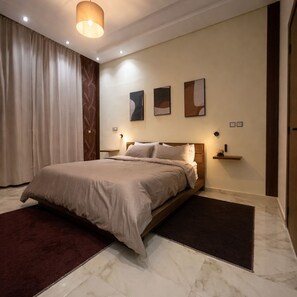 A modern bedroom with a large bed, a marble floor, and a large window with curtains. - Superb 2-bedroom apartment with AC in vibrant Rabat Agdal (Rabat)
