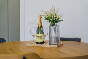 A bottle of wine, two glasses, and a vase with flowers on a wooden table. - Azahara Playa Suites (Los Cristianos)