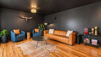 A modern living room with a leather sofa, two armchairs, a coffee table, and a wooden floor.