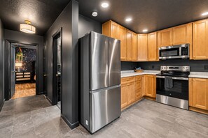Une cuisine moderne dotée d’appareils électroménagers en acier inoxydable, de meubles en bois et d’un plan de travail noir.