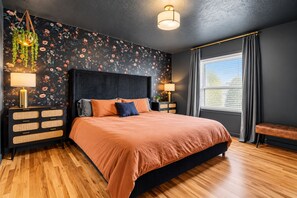 A bedroom with a large bed, dark walls, floral wallpaper, and a window with curtains. - Octopus Palace (Crescent)