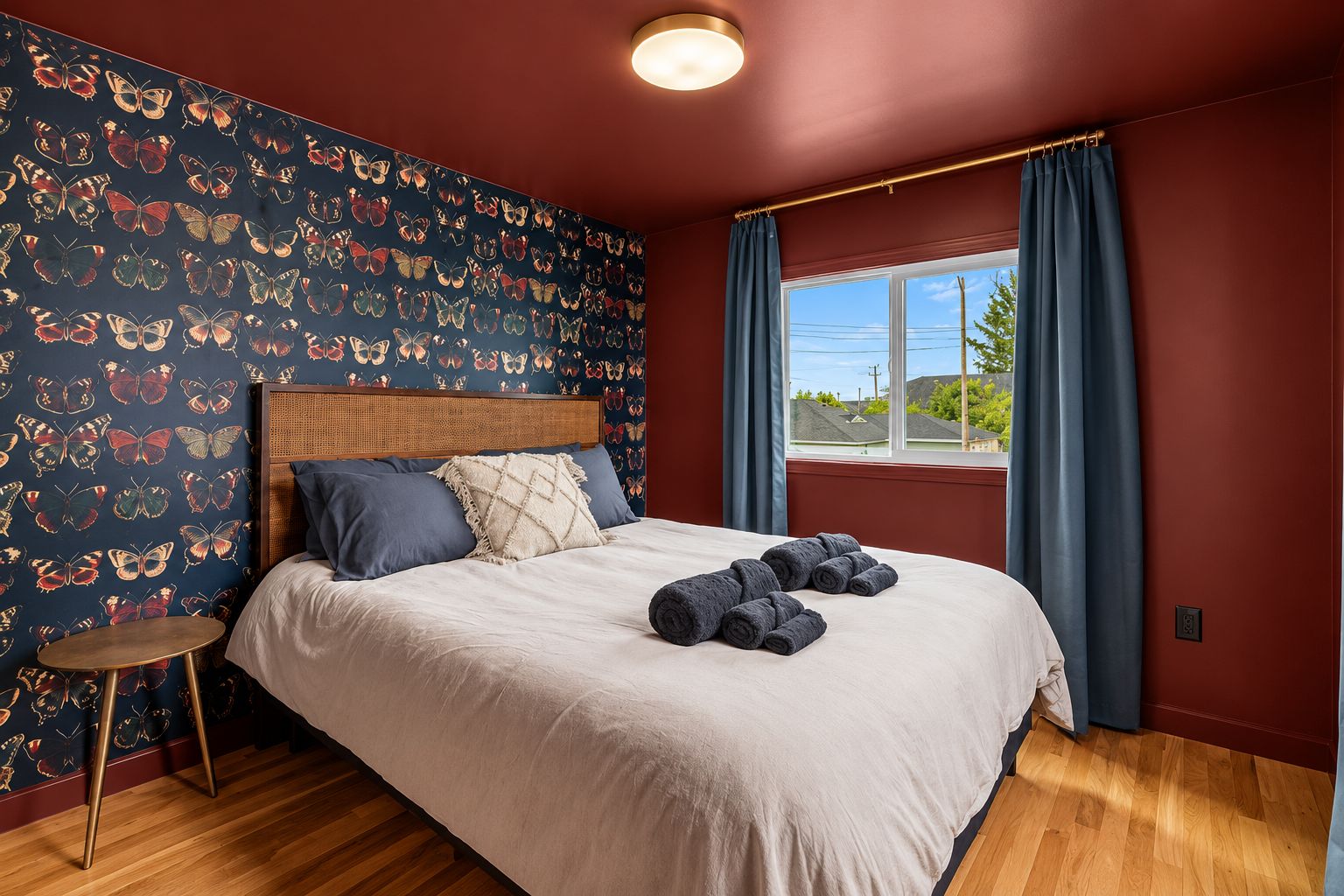 Ein Schlafzimmer mit einem Bett, einem Kopfteil, einem Fenster mit Vorhängen und einer Wand mit einem Schmetterlingsmuster.