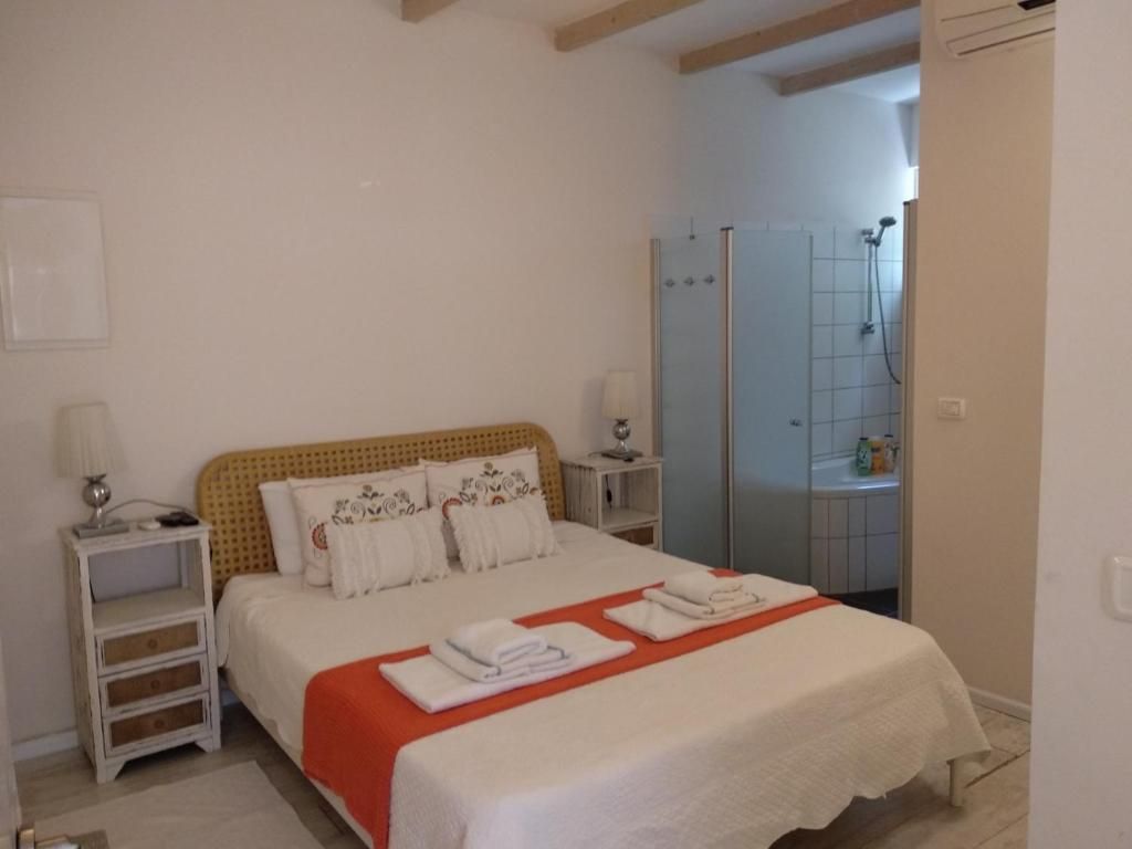 A bedroom with a bed, nightstands, a bathroom with a shower, and a door leading to another room.