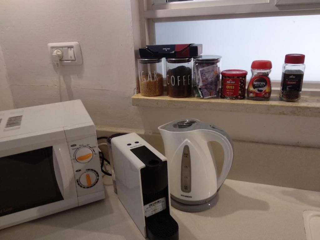 Eine Mikrowelle, eine Kaffeemaschine und ein Regal mit Kaffee und Gewürzbehältern.