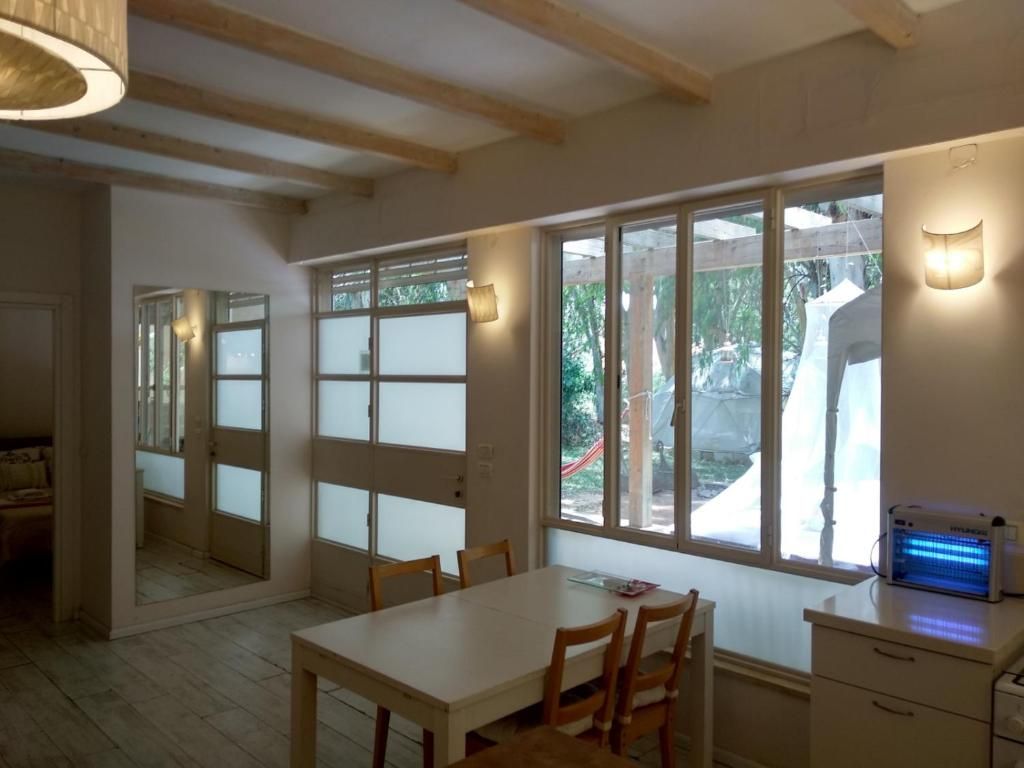 A room with a dining table, chairs, a heater, and large windows.