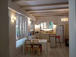 Une cuisine avec des poutres en bois, une table à manger avec des chaises et un réfrigérateur.