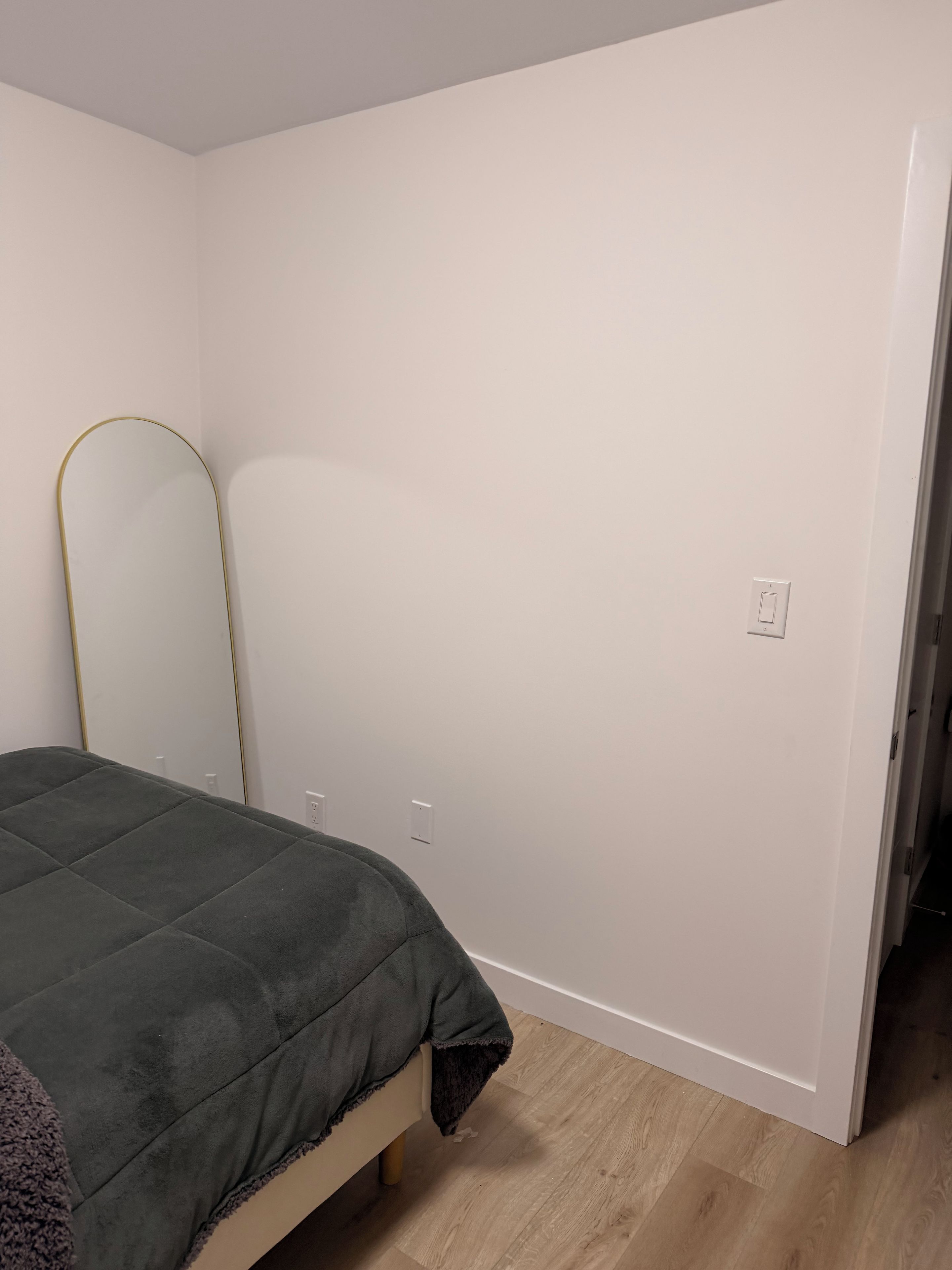 Ein Schlafzimmer mit einem Bett, einem Spiegel und einer Tür zu einem anderen Raum.