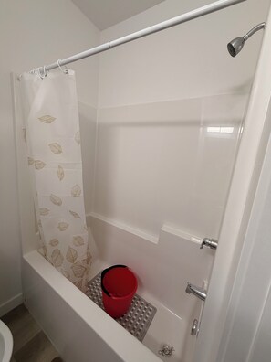 A shower area with a white shower curtain, a red bucket, and a showerhead. - Spacious well equipped bedroom and private washroom with a private entrance. (Winnipeg)