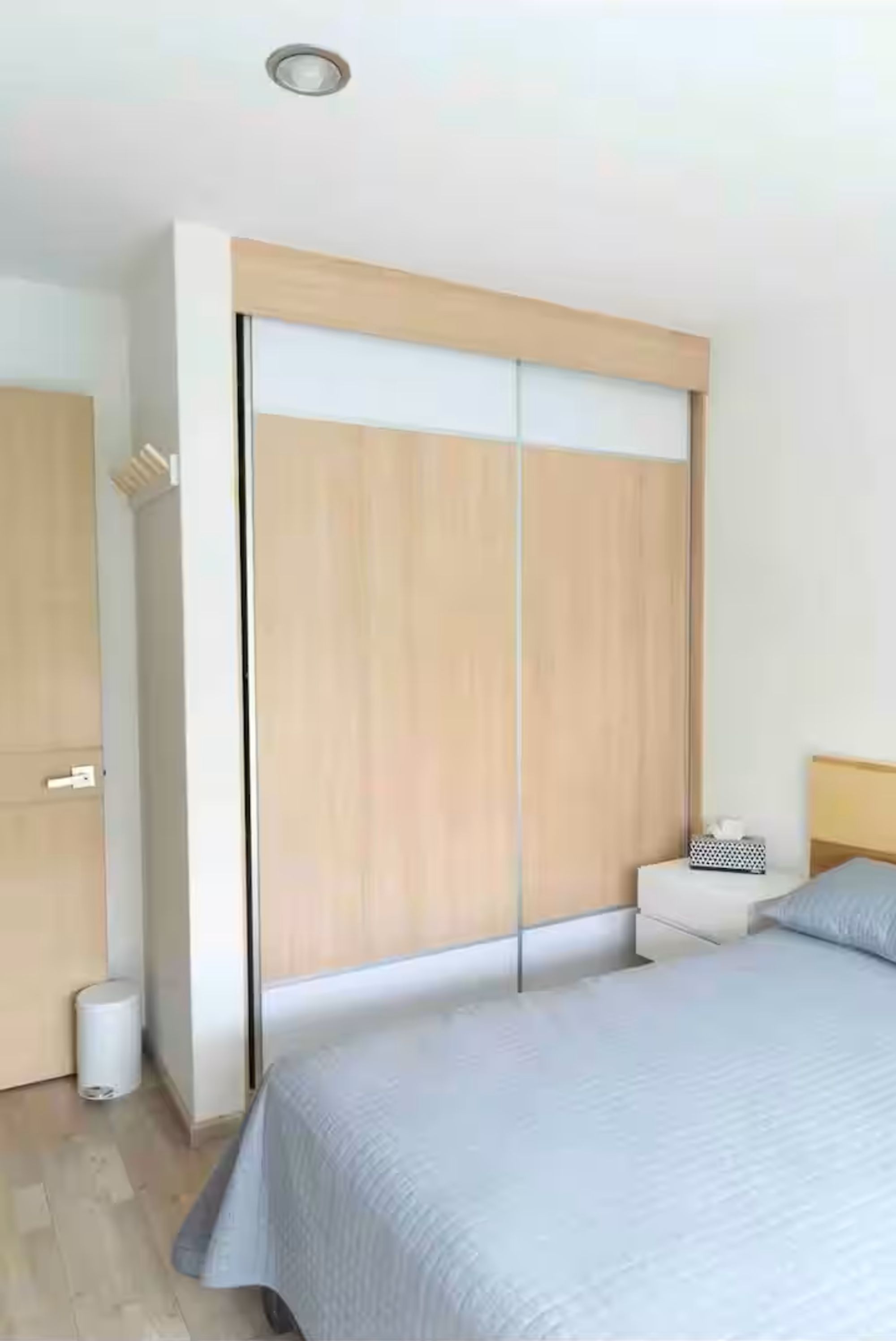 A bedroom with a bed, a wardrobe, and a bedside table.