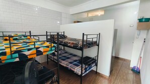 Pieni huone, jossa on kerrossängyt, pieni pöytä ja kattotuuletin.