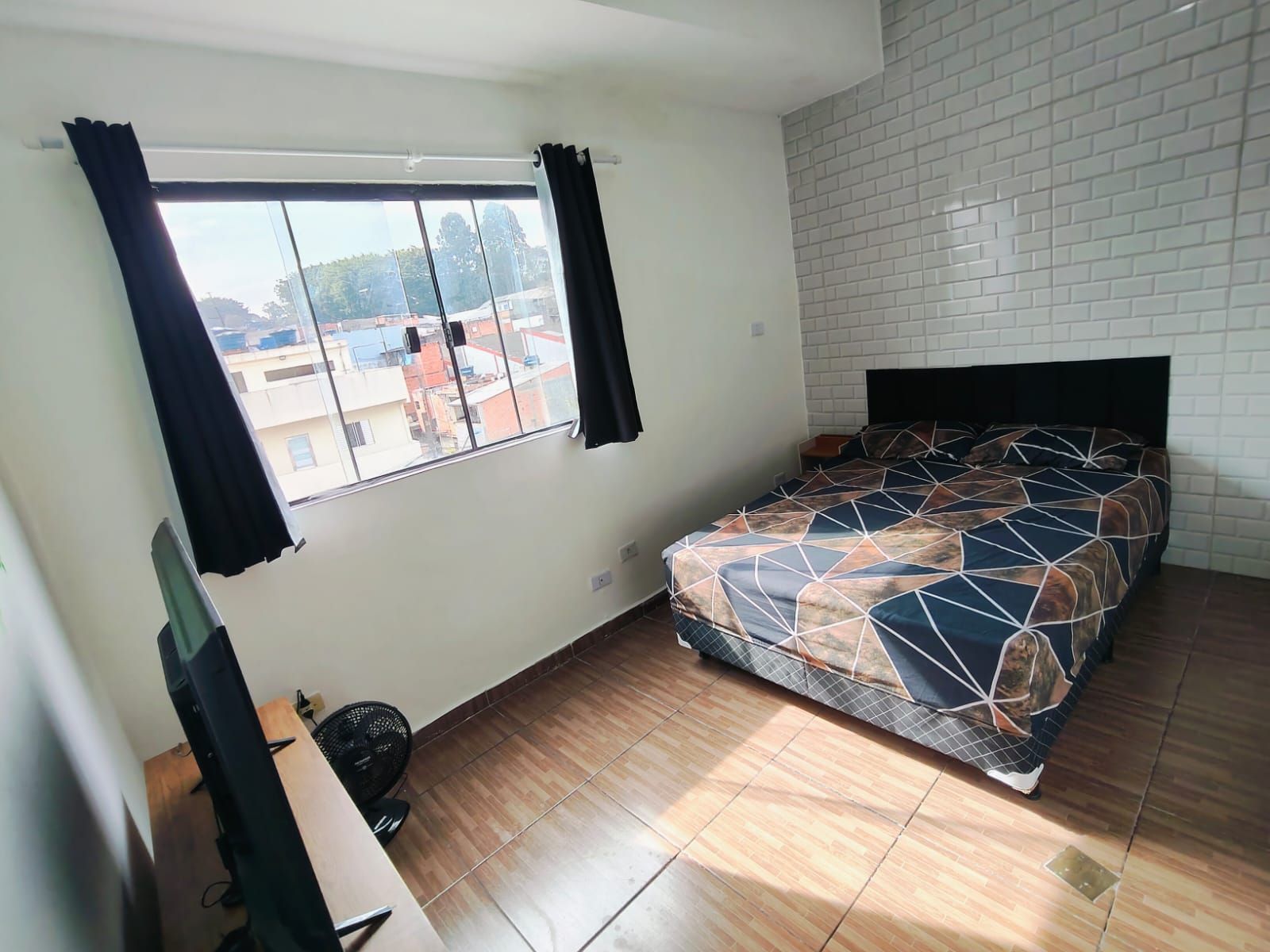 Een slaapkamer met een bed, een raam, een bureau en een stoel.