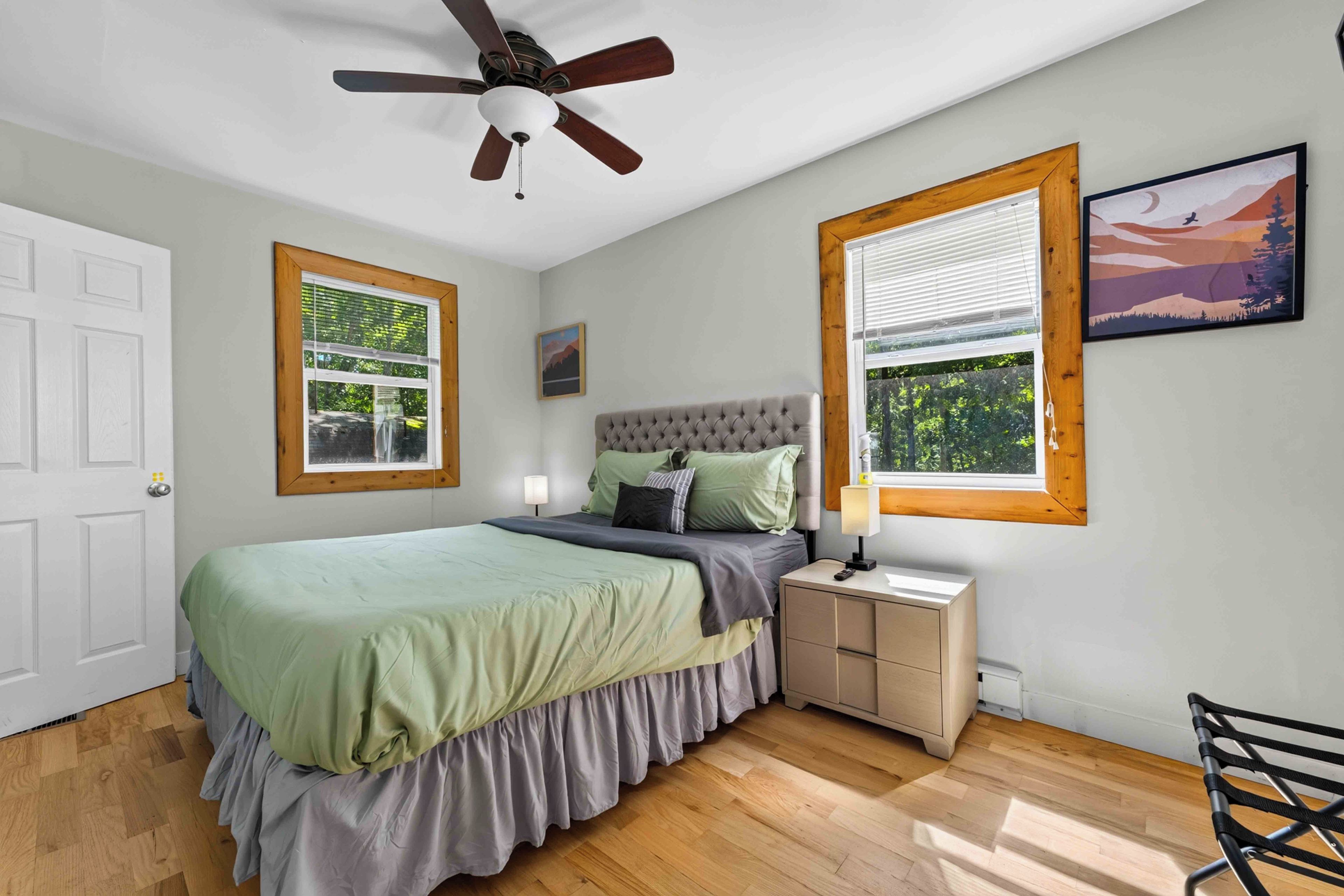 A bedroom with a bed, nightstand, lamp, and a ceiling fan.