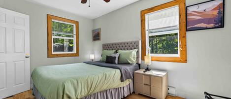 Ein Schlafzimmer mit Bett, Nachttisch, Lampe und Deckenventilator.
