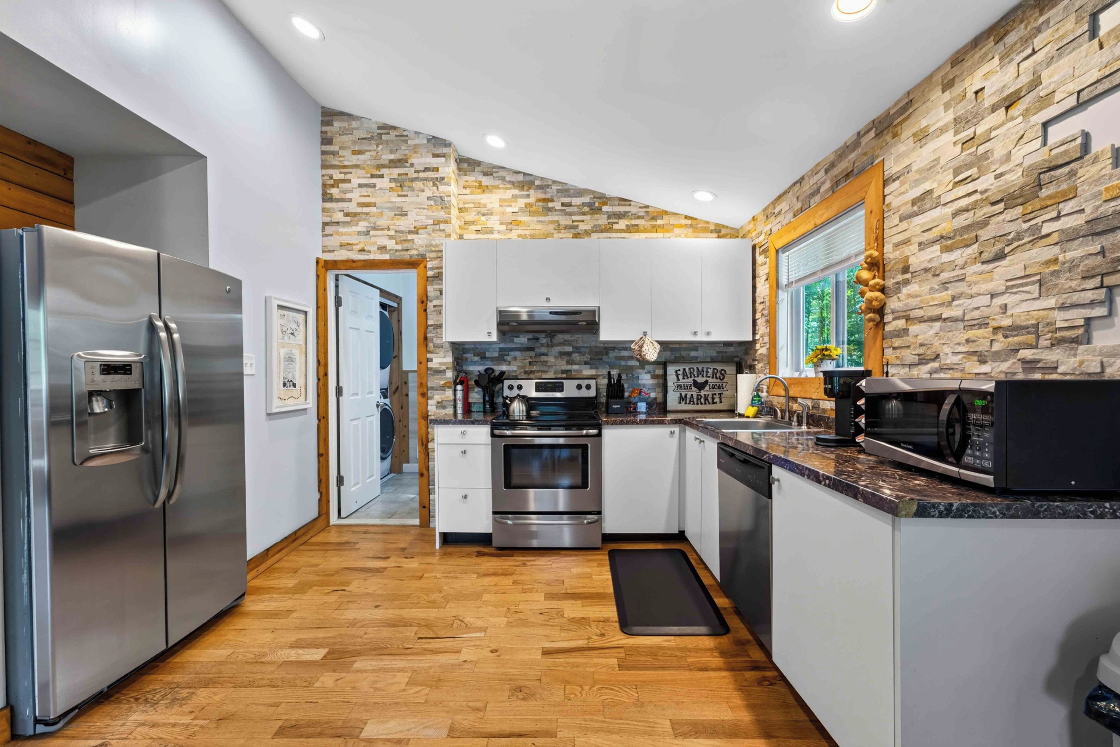 Una cocina moderna con salpicadero de pared de piedra, electrodomésticos de acero inoxidable y suelo de madera.