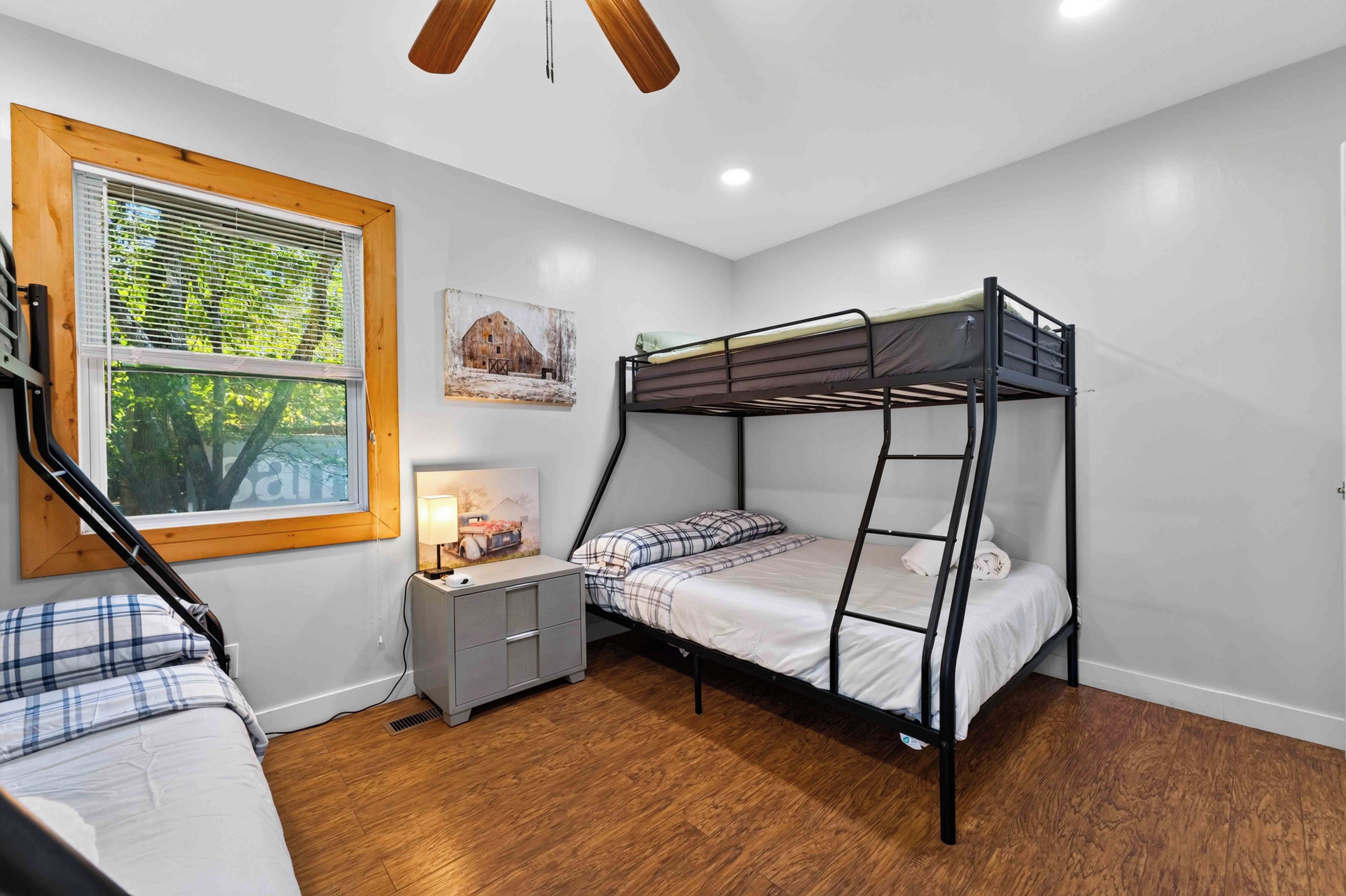 A bunk bed room with a window, a desk, and a lamp.