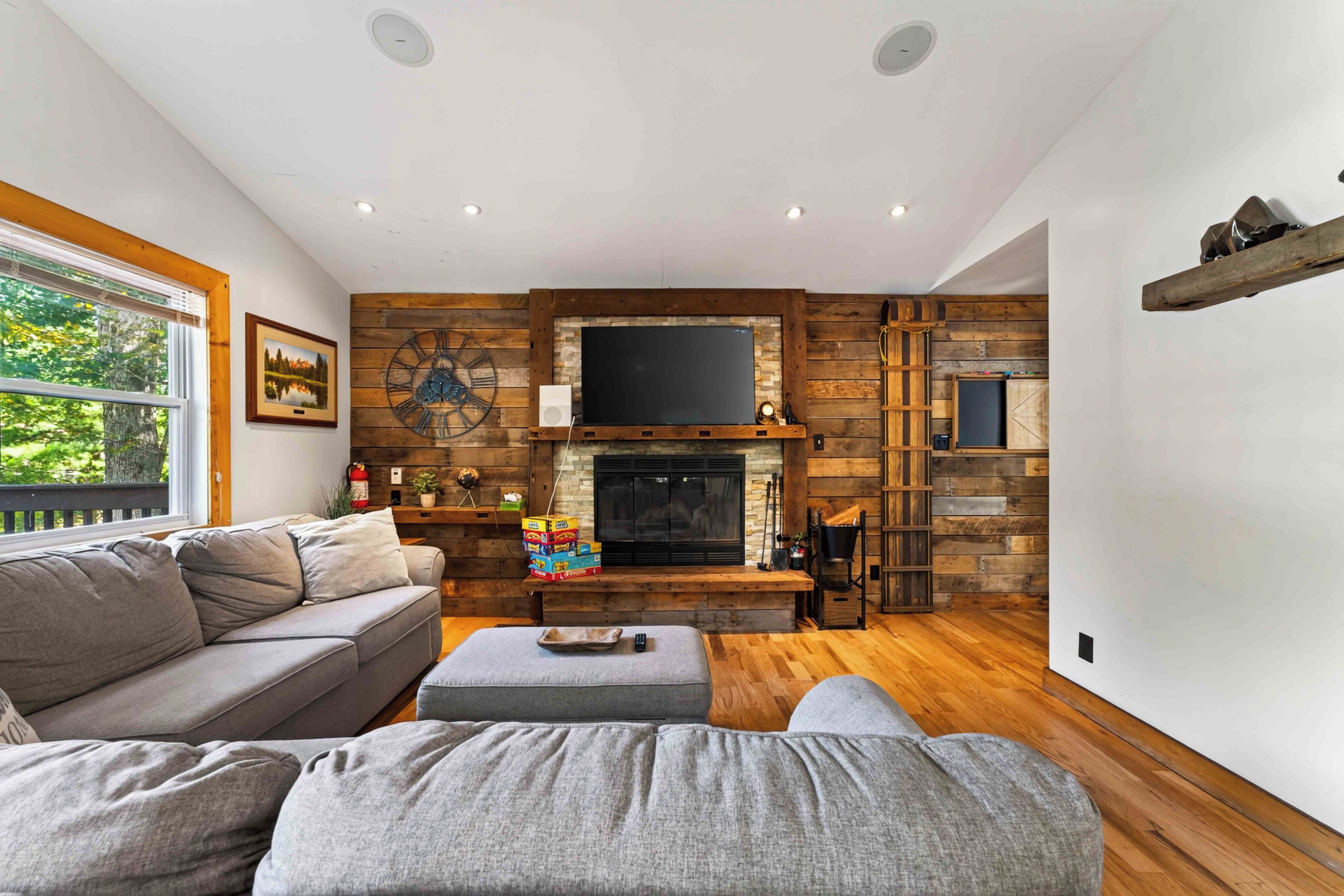 A living room with a fireplace, wooden walls, a sofa, and a television.
