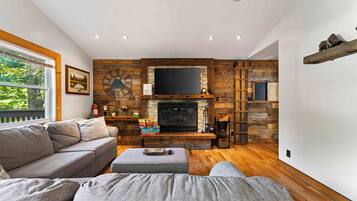 A living room with a fireplace, wooden walls, a sofa, and a television.