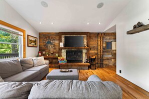 Una sala de estar con chimenea, paredes de madera, un sofá y un televisor.