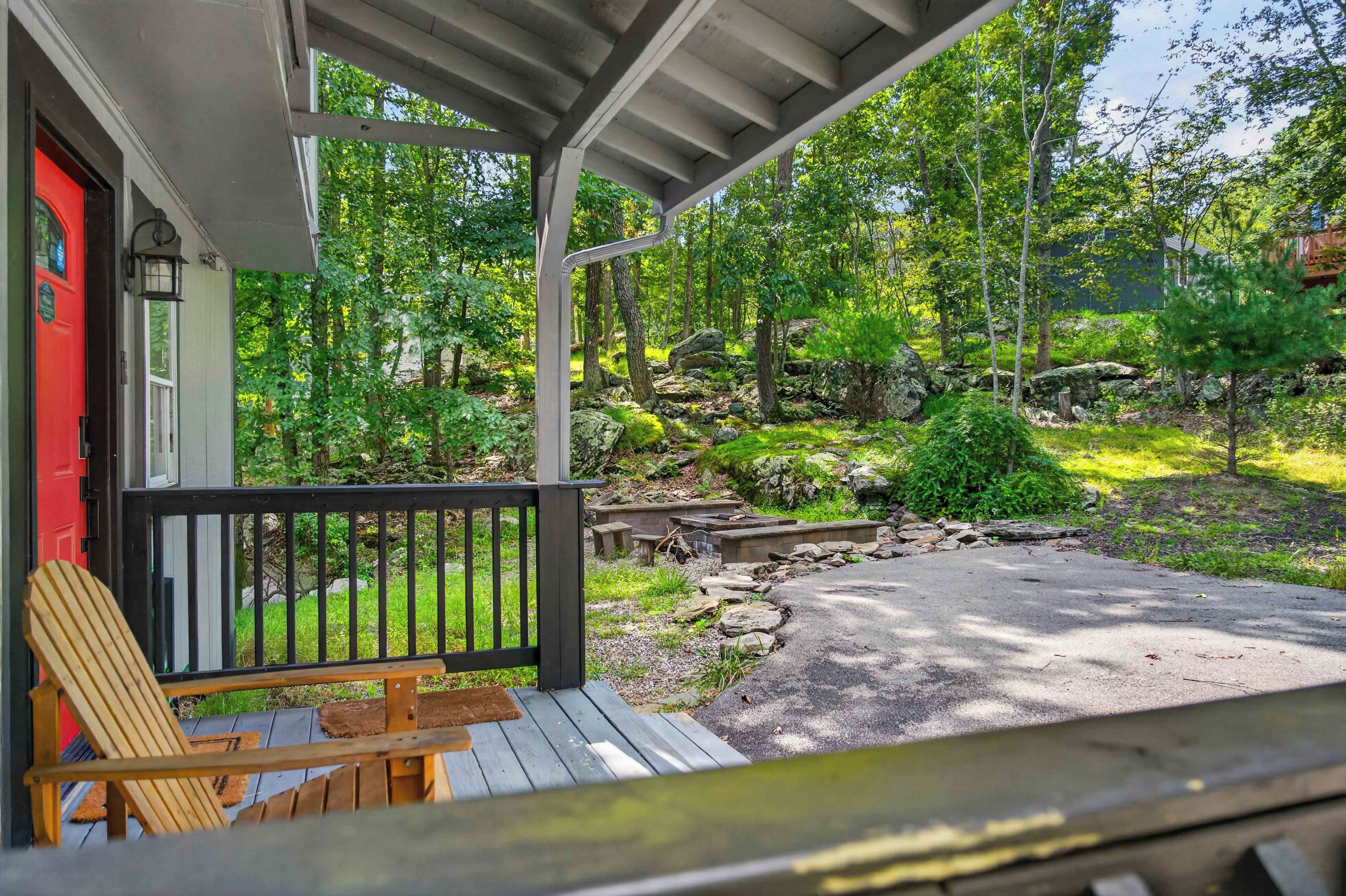 A covered porch with a wooden bench and a red door.