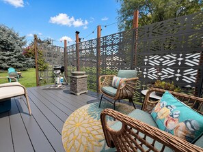 An outdoor deck with wicker furniture, a grill, and a decorative fence. - Cozy Cabin Glacier Getaway - Fireplace & Firepits (Kalispell)