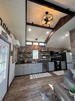 A spacious kitchen with a stone backsplash, modern appliances, and a wooden ceiling. - Cozy Cabin Glacier Getaway - Fireplace & Firepits (Kalispell)