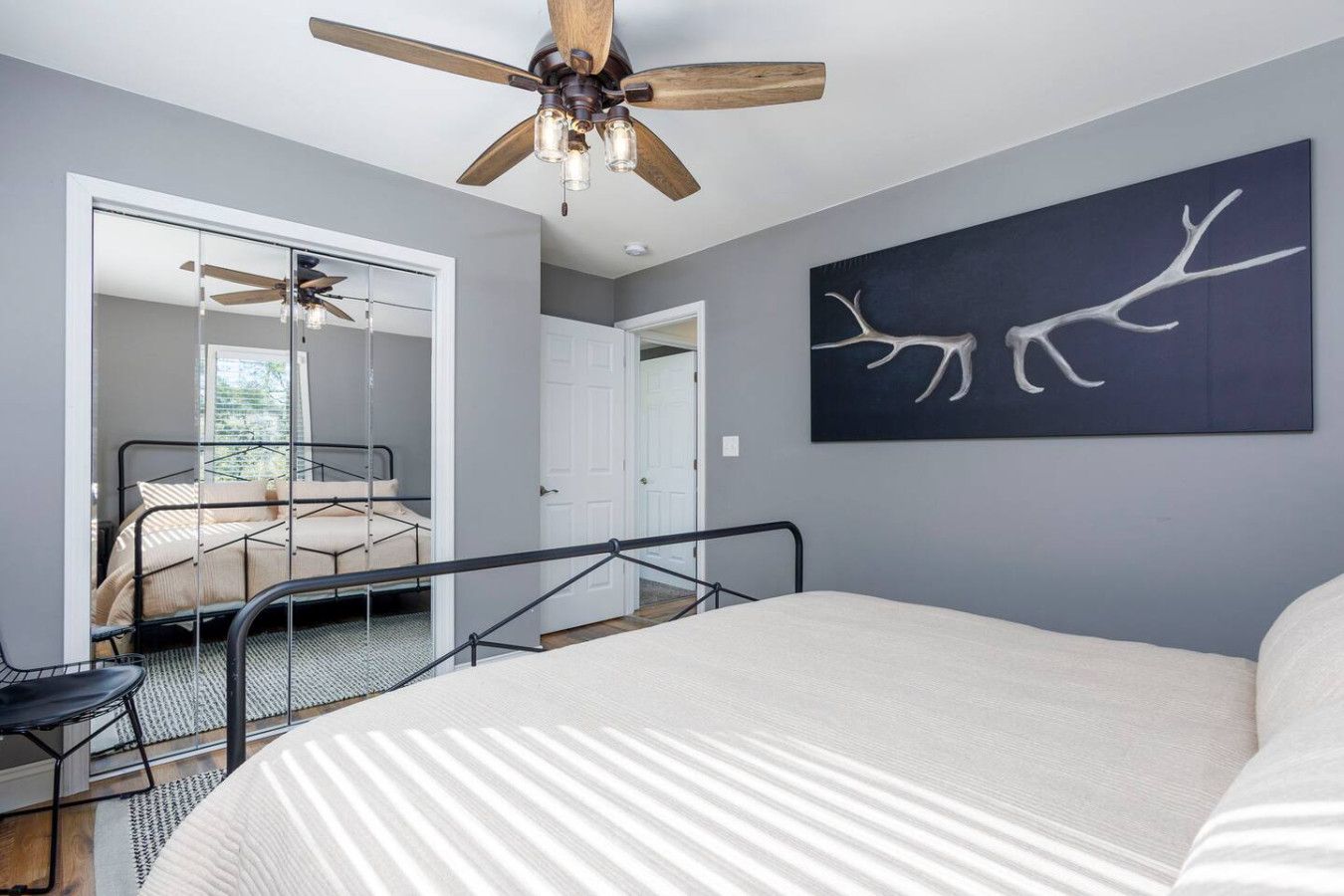 Une chambre à coucher avec un lit, un ventilateur de plafond, une œuvre d’art accrochée au mur et un escalier menant à une autre pièce.