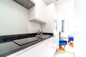 A modern kitchen with a black countertop, stainless steel sink, and white cabinets. - London Bridge Studios (London)