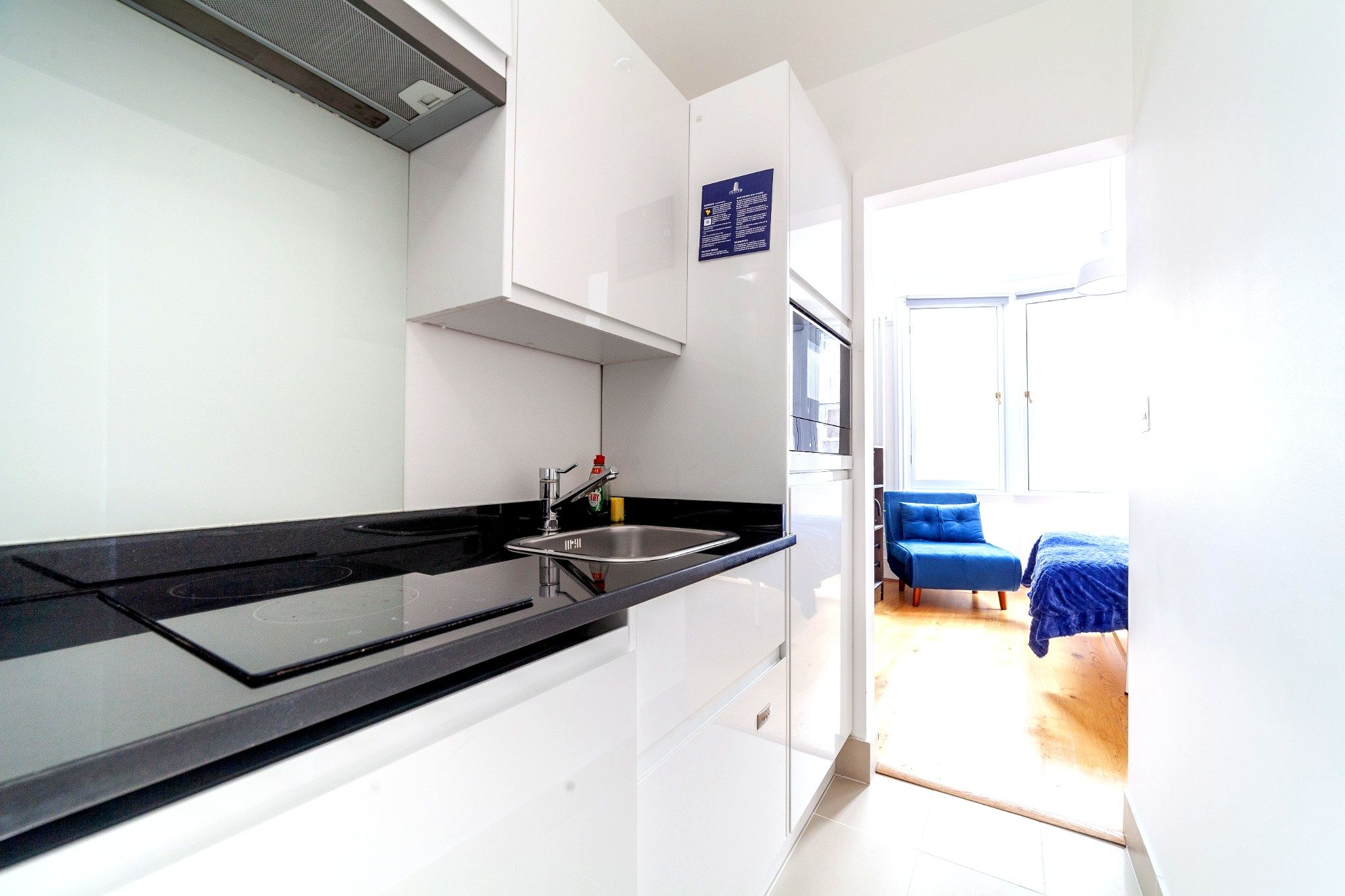 A modern kitchen with a black countertop, stainless steel sink, and white cabinets.
