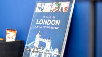 A book titled 'You're in London' on a wooden surface with a blue wall in the background.