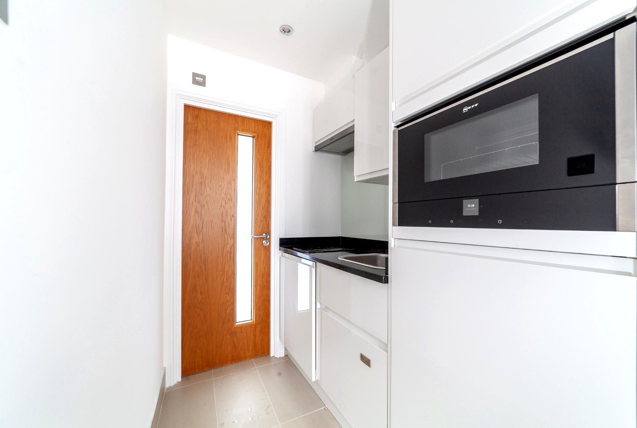 A kitchen with white cabinets, a black countertop, and a built-in oven.