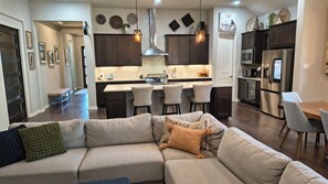 A modern kitchen with dark wood cabinets, a central island with bar stools, and stainless steel appliances. - Serene 3-bedroom house. Less than 5 minutes to restaurants and entertainment. (Georgetown)