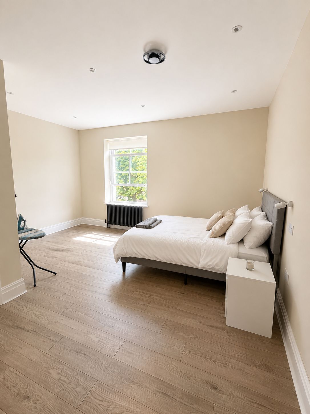 A bedroom with a bed, bedside table, and a window.