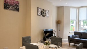 A dining area with a table set for four, a sofa, and a fireplace.