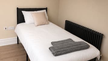 Quarto com cama, radiador e piso de madeira.