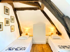 A small, cozy attic bedroom with two beds, wooden beams, and framed pictures on the wall. - Magnanerie du manoir de Beauregard (Véretz)