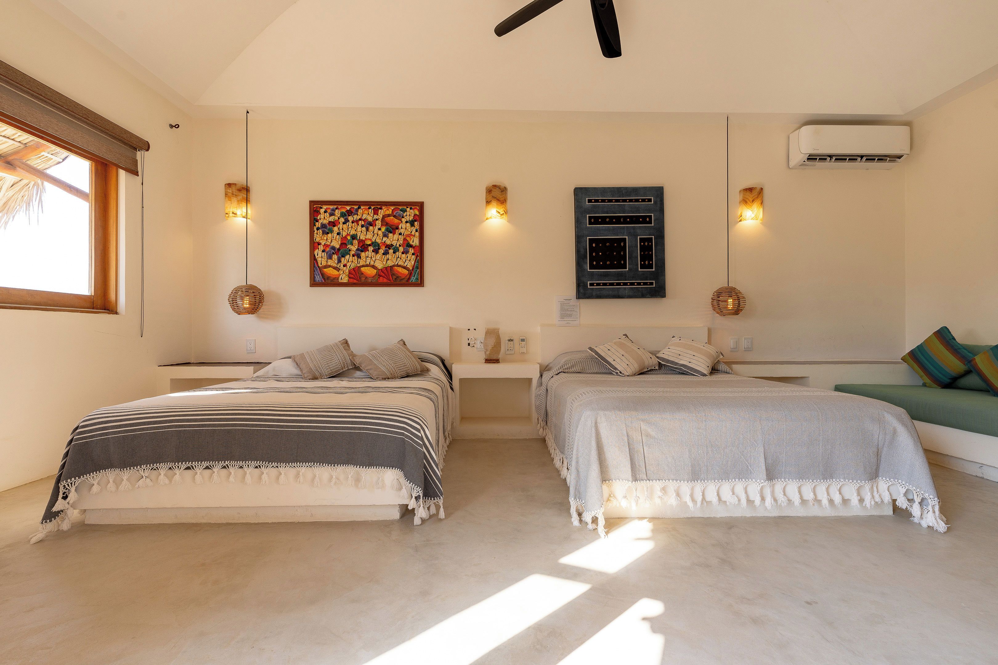 Ein Schlafzimmer mit zwei Betten, einem Deckenventilator, einer Klimaanlage und einem Bild an der Wand.
