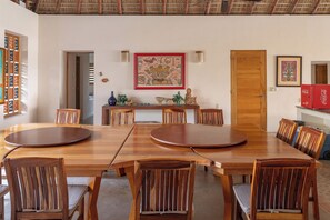 A dining area with a large wooden table and chairs, a door, and a wall with a framed picture. - Ventana al Paraíso Oceanfront Villa (Bajos de Chila)