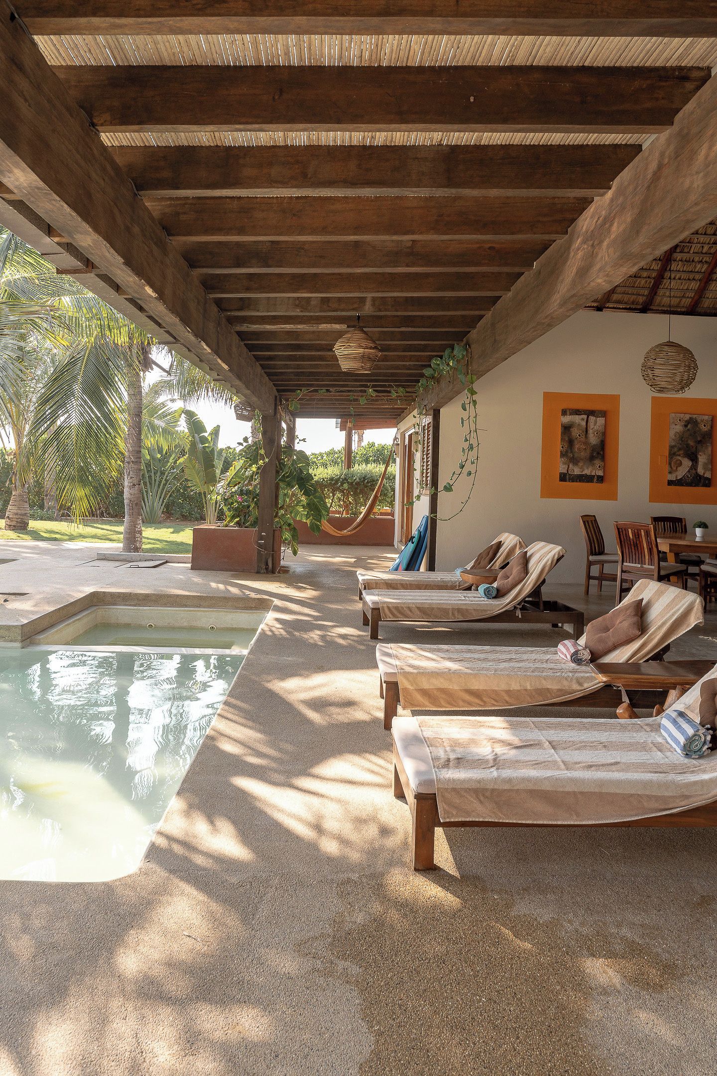 Espaço ao ar livre coberto com piscina, espreguiçadeiras e área de refeições.