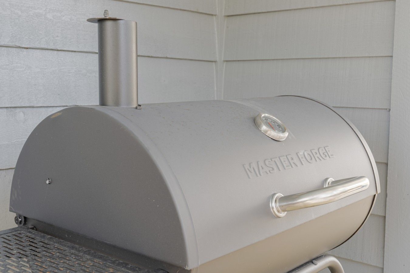 A barbecue grill with a metallic finish and a handle on the side.