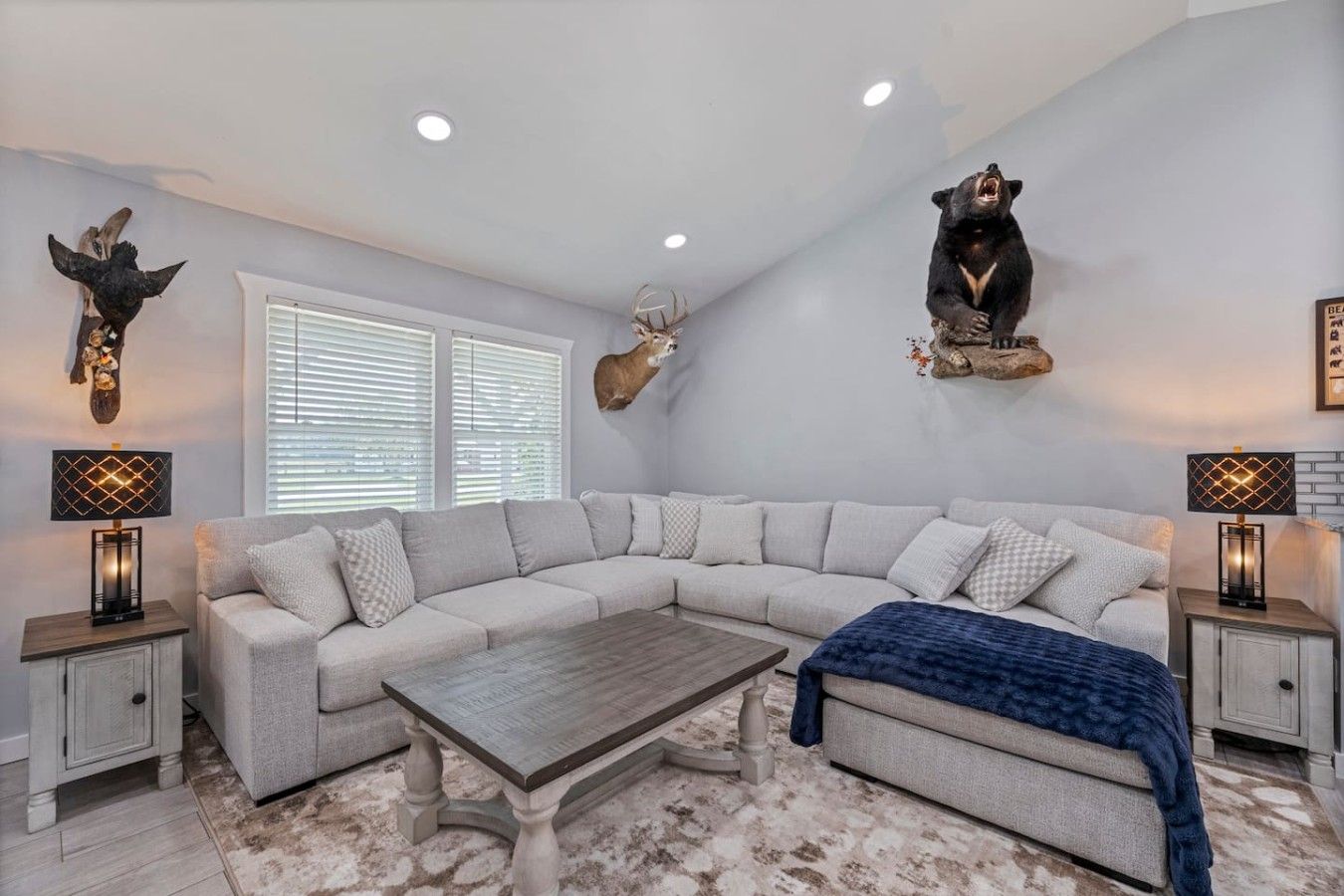 A modern living room with a sectional sofa, a coffee table, and decorative animal mounts on the walls.